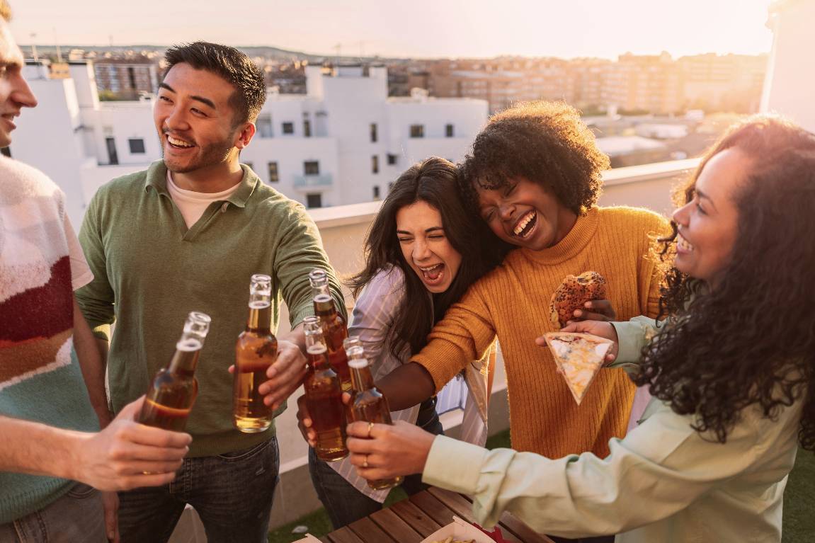 5 people sitting a roof ledge having a nice time