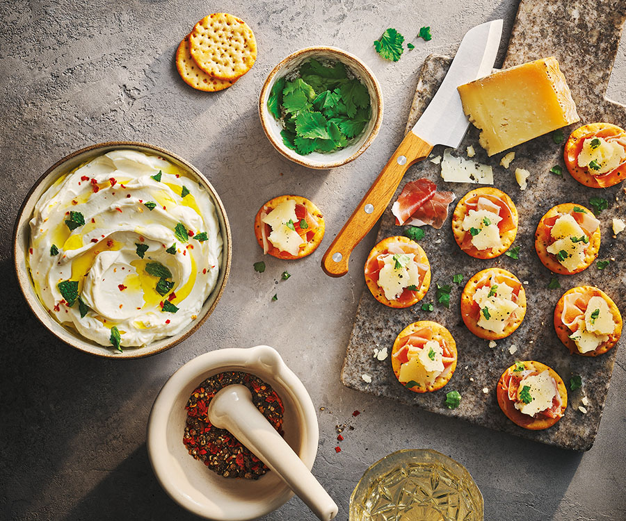 Toasteds Crackers shown with dips and toppings on a counter top.