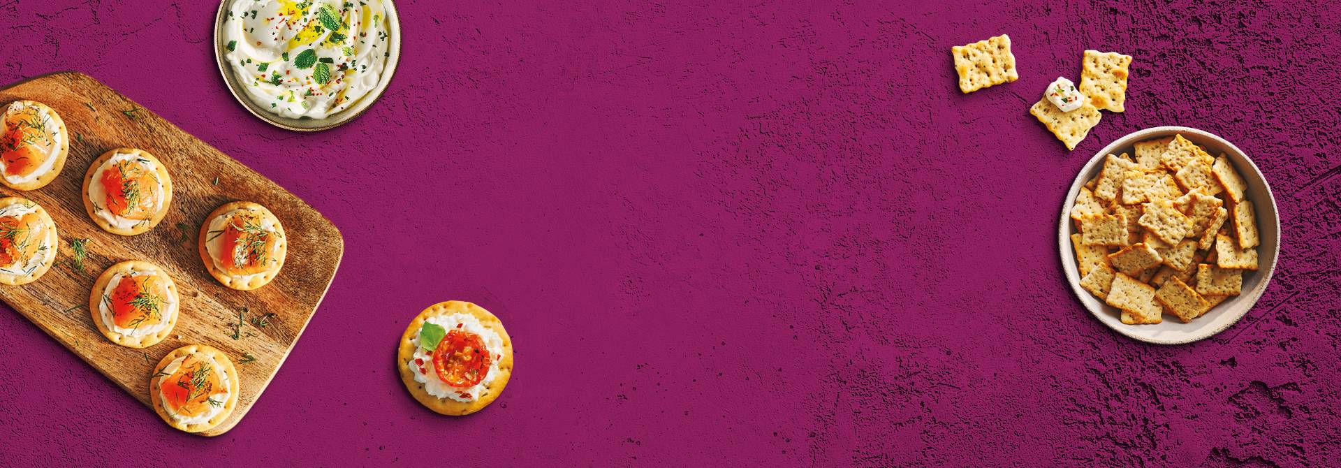 Toasteds Crackers shown in bowls and on plates. Displayed on a purple texture background.